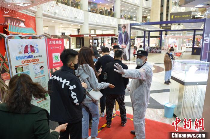 圖為商場門口測體溫時，工作人員讓顧客排隊保持距離。　劉文華 攝